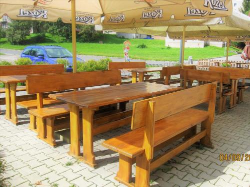 a group of wooden benches sitting under an umbrella at Pension Žacléřský Medvěd in Žacléř