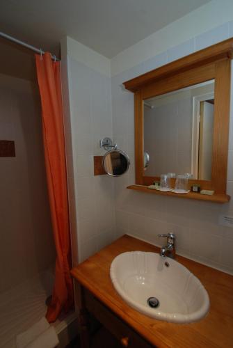 a bathroom with a sink and an orange shower curtain at Logis Cote Loire - Auberge Ligerienne in Blois