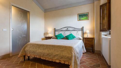 sypialnia z łóżkiem z zielonymi poduszkami w obiekcie Borgo Pie' di Gamboi w mieście Chianni