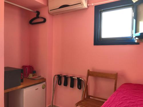 Habitación con cama, ventana y nevera. en Fraskoula's Town en Mykonos ciudad