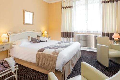 une chambre d'hôtel avec un lit et une chaise dans l'établissement Logis La Thomasse, à Aurillac