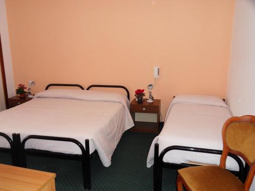 two beds in a room with two tables and chairs at Albergo Betulla in Onore