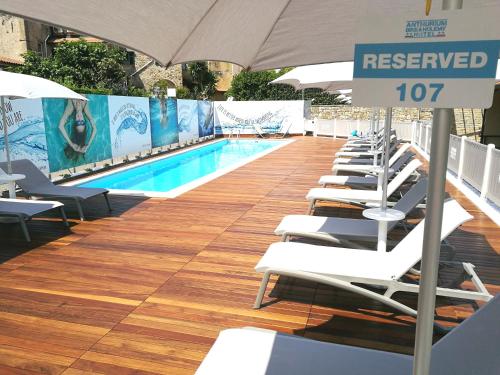 a row of lounge chairs next to a swimming pool at Best Western Hotel Anthurium in Santo Stefano al Mare