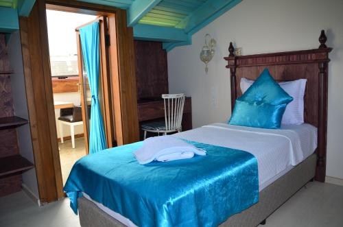 a bedroom with a bed with blue sheets and a desk at Orchis Hotel in Ayvalık