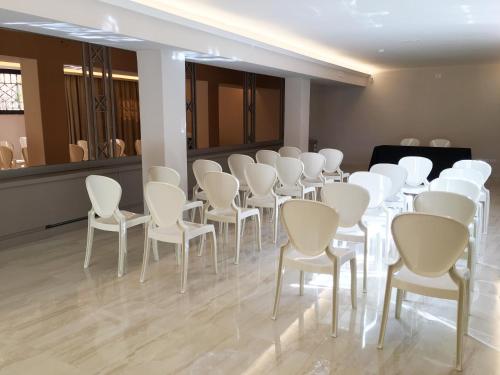 a room with white chairs and a table and a mirror at Hotel De La Ville in Riccione