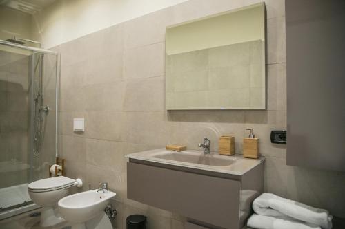 een badkamer met een wastafel, een toilet en een spiegel bij Al Tartarughino B&B in Cercola