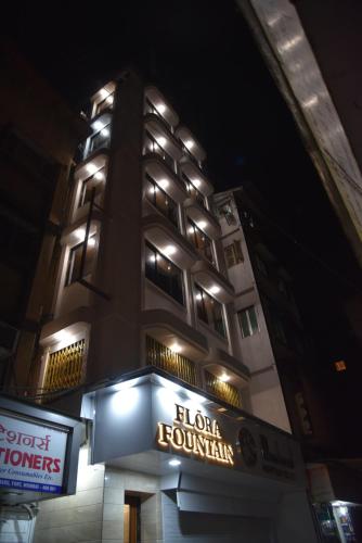 un bâtiment avec un panneau devant lui la nuit dans l'établissement Hotel Flora Fountain,Fort, à Mumbai