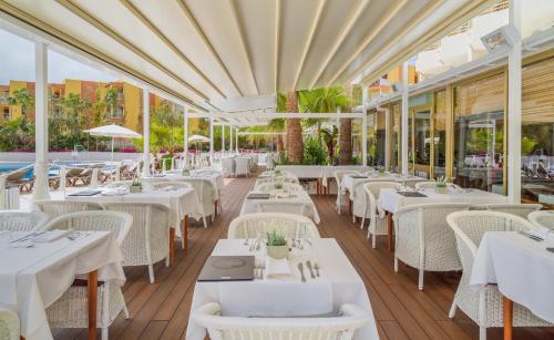 a restaurant with white tables and white chairs at H10 Cambrils Playa in Cambrils