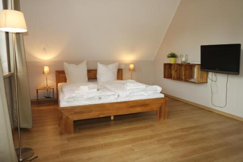 a bedroom with a bed with white sheets and a tv at Appartements Fischerhus in Glowe
