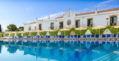 a pool with chairs and umbrellas in front of a building at Globales Pueblo Andaluz in Marbella