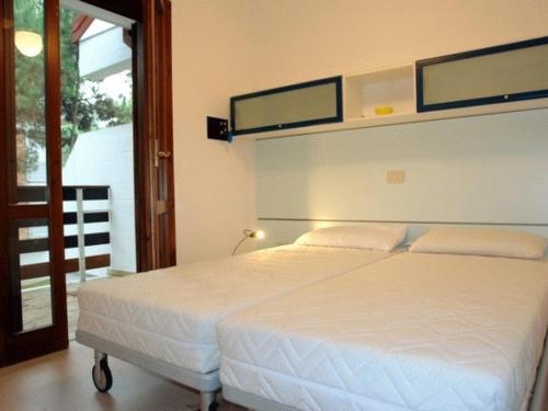 a bedroom with a white bed and a balcony at Lignano Pineta very nice in Lignano Sabbiadoro