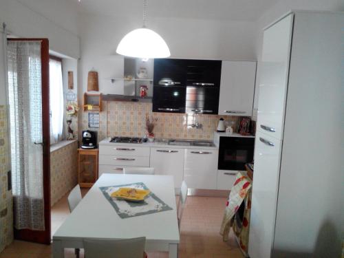 - une cuisine avec des placards blancs et une table blanche dans l'établissement Appartamento Gianluca, à SantʼAntìoco