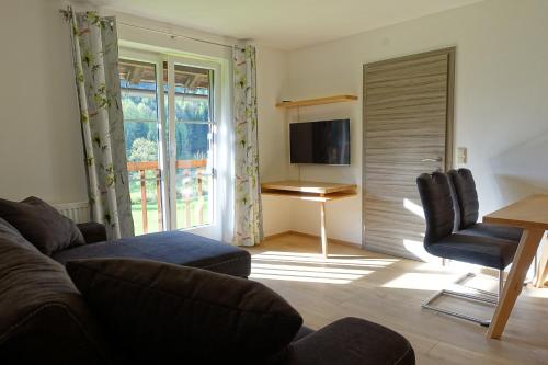 a living room with a couch and a table and a television at Urlauben im Grünen in Fuschl am See