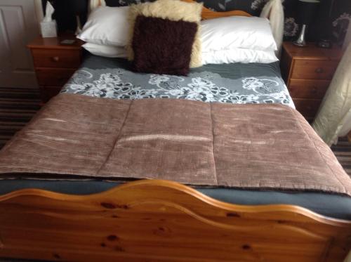 a bed with a wooden frame with a blanket on it at Sherwood Lodge in Skegness