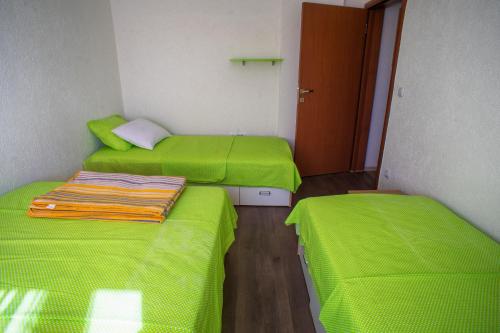 two beds in a small room with green sheets at Apartmani Restoran Durmitor in Žabljak