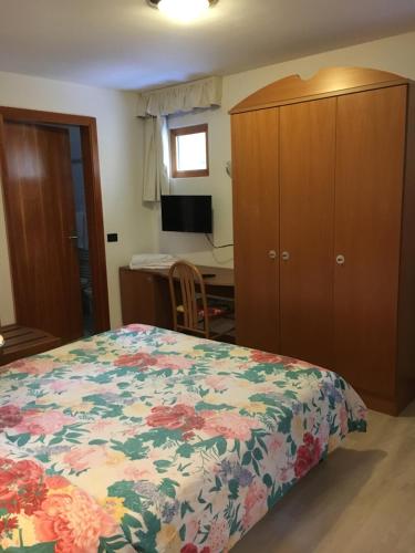 a bedroom with a bed and a dresser and a desk at Garni Enrosadira in Vigo di Fassa