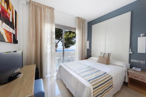 a bedroom with a bed and a tv and a window at Sandos El Greco - Adults Only in Portinatx