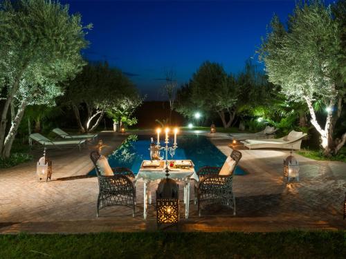 a dinner table in front of a pool at night at VILLA PASCHMINA PISCINE CHAUFFEE in Ourika