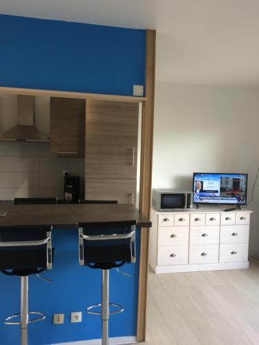 une cuisine avec des murs bleus et un comptoir avec des tabourets dans l'établissement Studio Opale, à Berck-sur-Mer