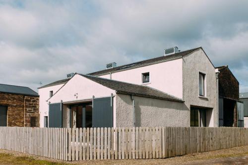a white house behind a wooden fence at Incheoch Farm Granary in Alyth