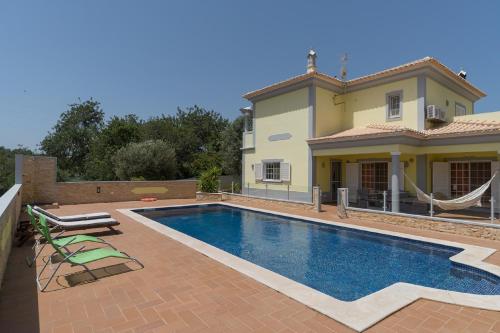 a swimming pool in front of a house at Akivillas Pera Relax II in Alcantarilha