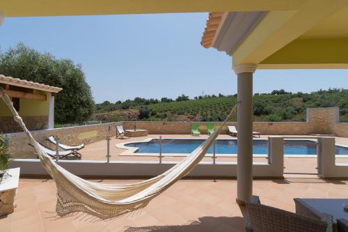 a hammock on a patio with a swimming pool at Akivillas Pera Relax II in Alcantarilha