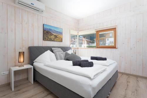 1 cama blanca grande en una habitación con ventana en Designferienhaus Altenmarkt Zauchensee, en Altenmarkt im Pongau