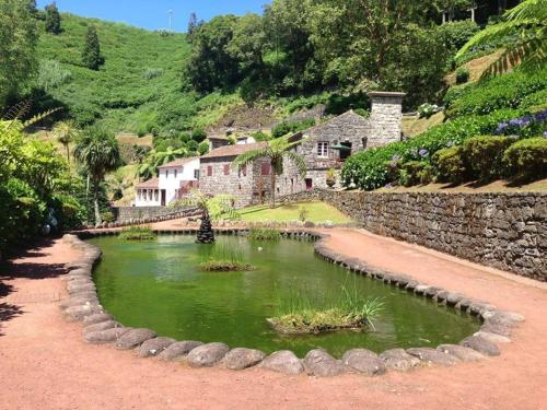 a small pond in front of a stone house at Pérola Achadense Guesthouse in Achada