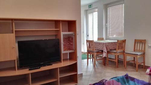 Una sala de estar con un televisor y una mesa con sillas. en Apartments Bernarda, en Bled
