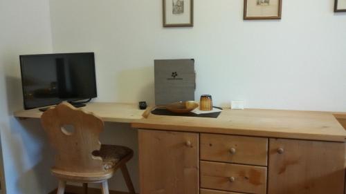 einen Holzschreibtisch mit einem TV und einem Stuhl in der Unterkunft Garni Raffein in Lana