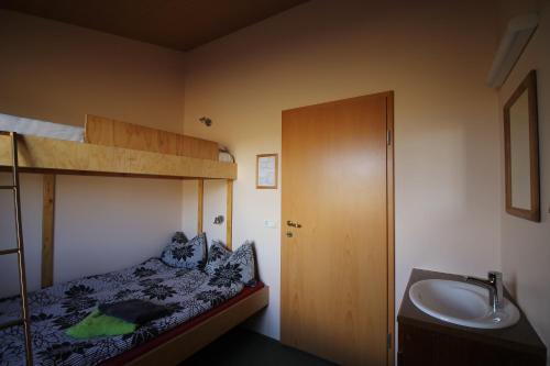 a small bedroom with a bunk bed and a sink at Hvoll Hostel in Kirkjubæjarklaustur