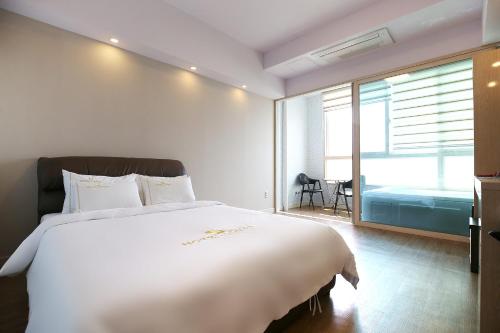 a bedroom with a large white bed and a window at Hotel Lohas in Boryeong