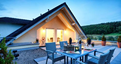a patio with a table and chairs and a house at Hotel Erasmus - Mein Genuss- und Wellnesshotel in Trassem