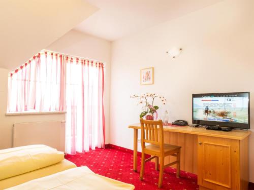 a bedroom with a television and a desk with a chair at Landhof Steinbäck in Sankt Stefan ob Stainz
