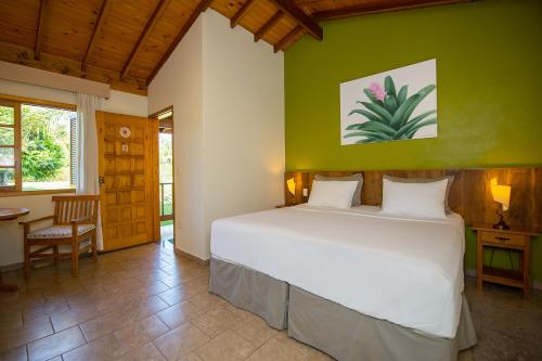 a bedroom with a white bed and a green wall at Pousada Paiol in Atibaia