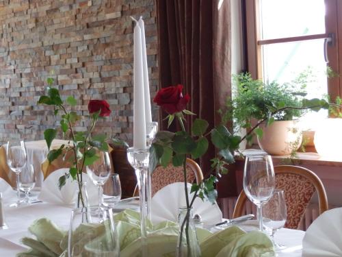 a table with wine glasses and red roses in vases at Gasthof Löwen, Heitersheim in Heitersheim