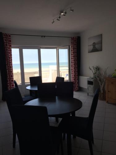 a dining room with a table and chairs and a large window at Les Chambres d'Hôtes de la Mer in Merlimont