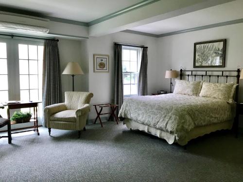 a bedroom with a bed and a chair and windows at The Old Lyme Inn in Old Lyme