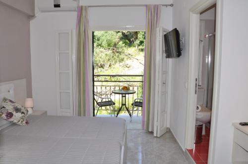 a bedroom with a bed and a balcony with a table at Angels Pool Studios and Apartments in Paleokastritsa