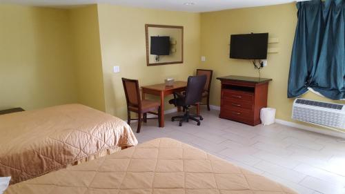 a bedroom with a bed and a desk and a television at Budget Motel in Orlando