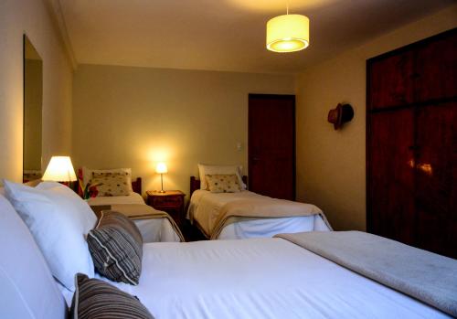 a hotel room with three beds and two lamps at Hotel Las Cascadas in La Cumbrecita