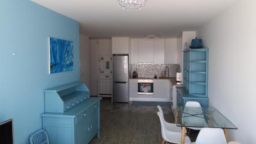 a kitchen with blue cabinets and a glass table at Blue Anchor Apartment in Vila Praia de Âncora