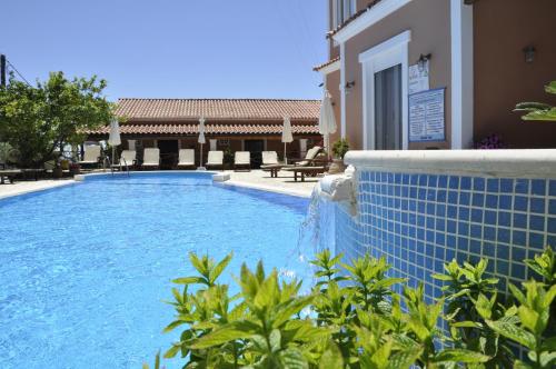 a swimming pool with a blue tile fence next to a building at Angels Pool Studios and Apartments in Paleokastritsa