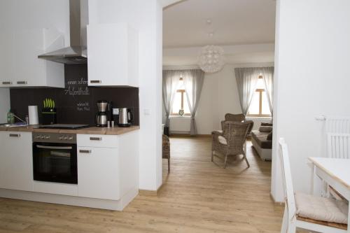 a kitchen with white cabinets and a living room at Ferienwohnungen EULE in Lutherstadt Wittenberg