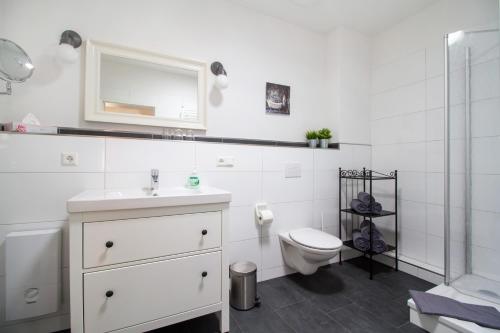 a white bathroom with a sink and a toilet at Ferienwohnungen EULE in Lutherstadt Wittenberg