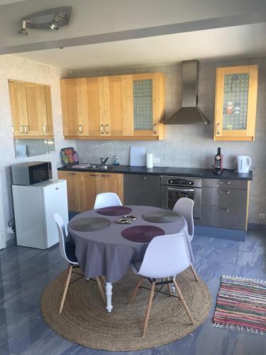 une cuisine avec une table et des chaises blanches dans l'établissement L'eau Vive Front de mer 4e sans ascenseur, à Le Touquet-Paris-Plage