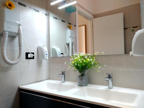 ein Badezimmer mit einem Waschbecken, einem Spiegel und Blumen in der Unterkunft Apartment Nice Venice in Mestre