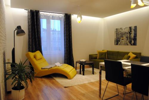 a living room with a yellow chair and a couch at Apartament Zwycięstwa 98 in Koszalin