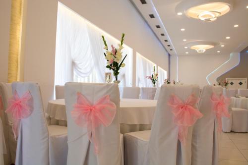 a room with white chairs and tables with pink bows at King Hotel in Peje