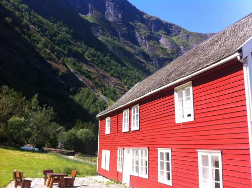 a red building with a mountain in the background at Brekke Gard Hostel in Flåm